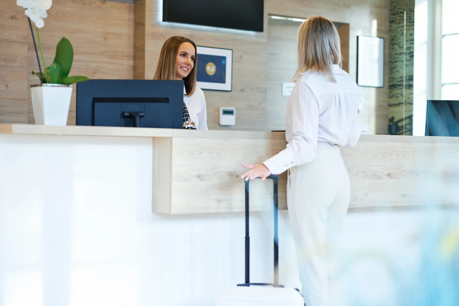 A guest with a suitcase speaking to a receptionist at a desk