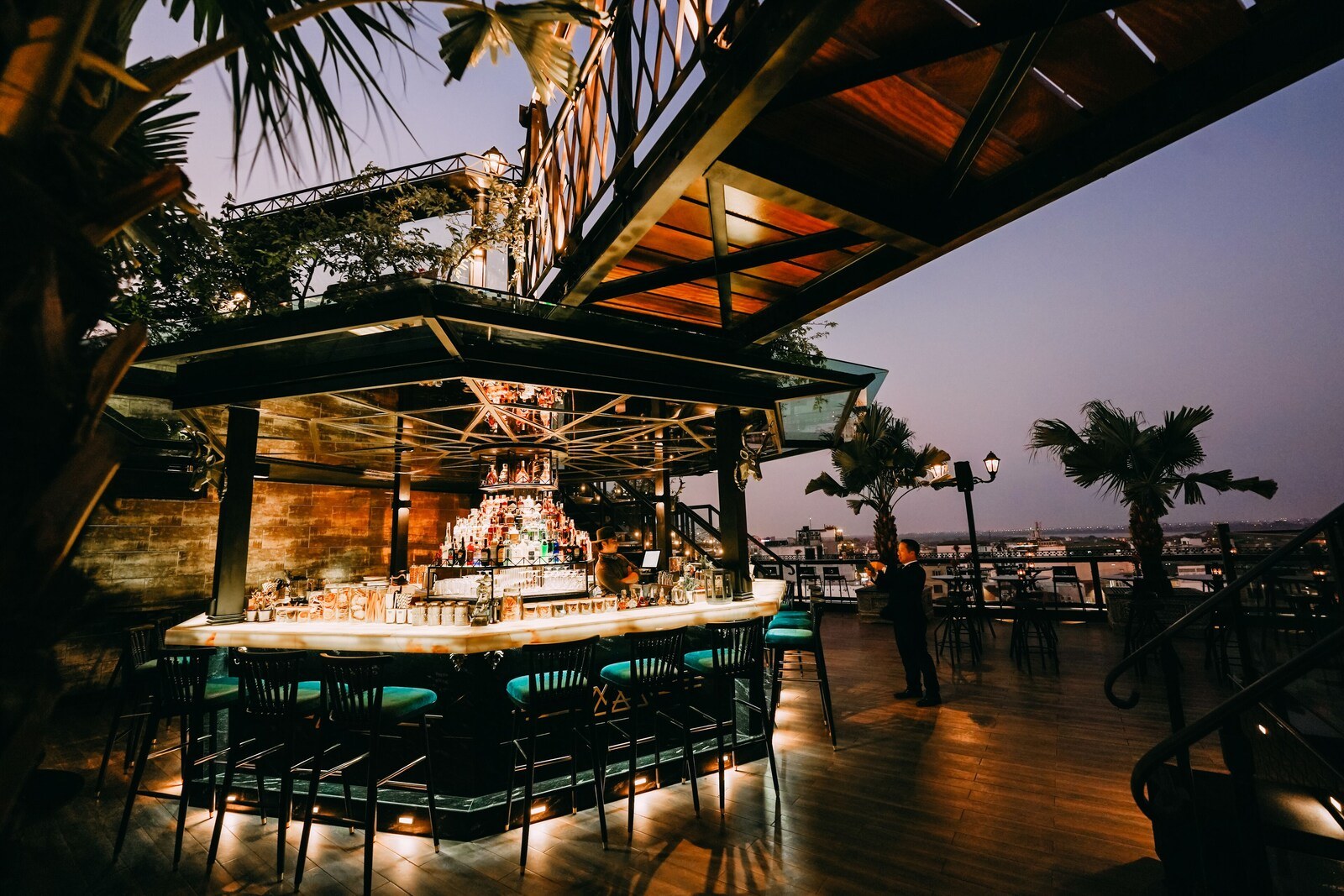 An outdoor bar area with a bar counter, seating, and a view of the cityscape. - La Siesta Classic Ma May (Hanoi)