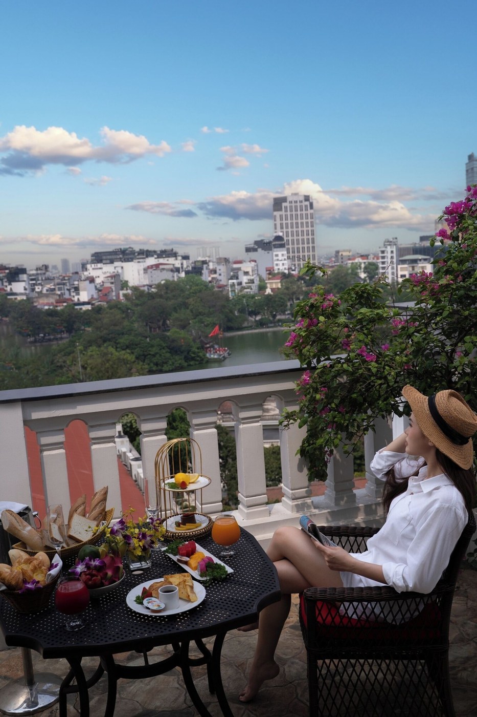 A balcony with a table set for breakfast, overlooking a cityscape. - The Oriental Jade Hotel (Hanoi)