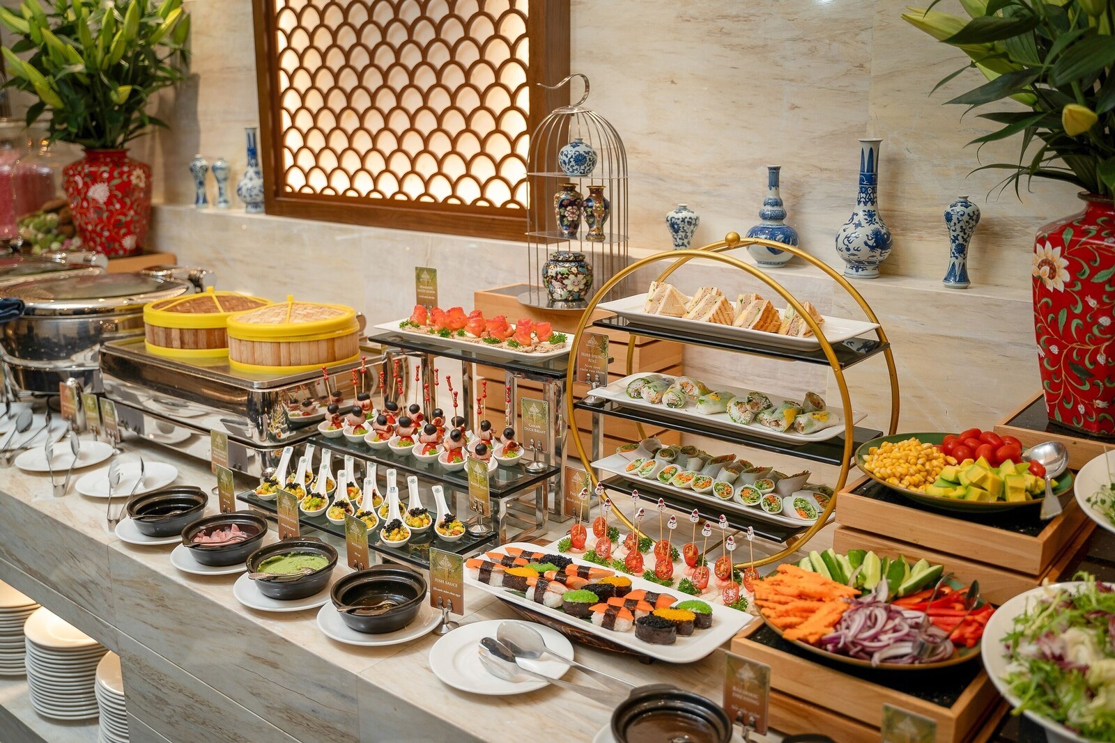 A buffet with various food items and decorative vases. - The Oriental Jade Hotel (Hanoi)