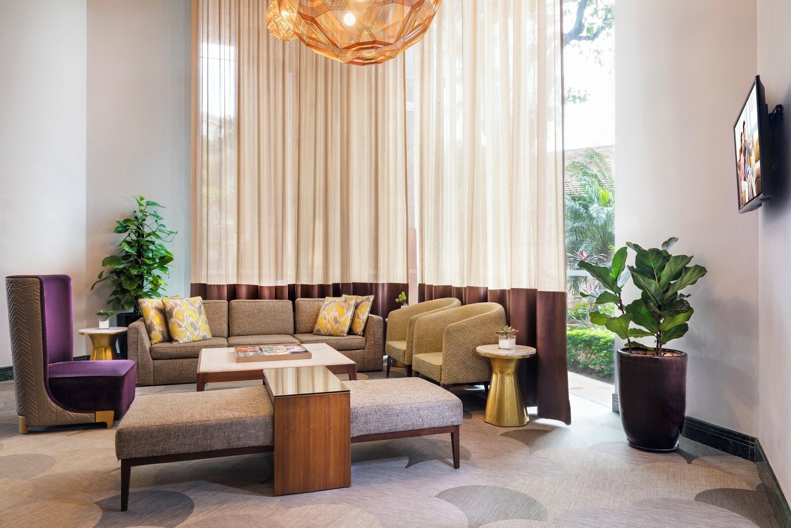 A modern living room with a sectional sofa, a coffee table, and a potted plant. - Somerset Grand Hanoi (Hanoi)