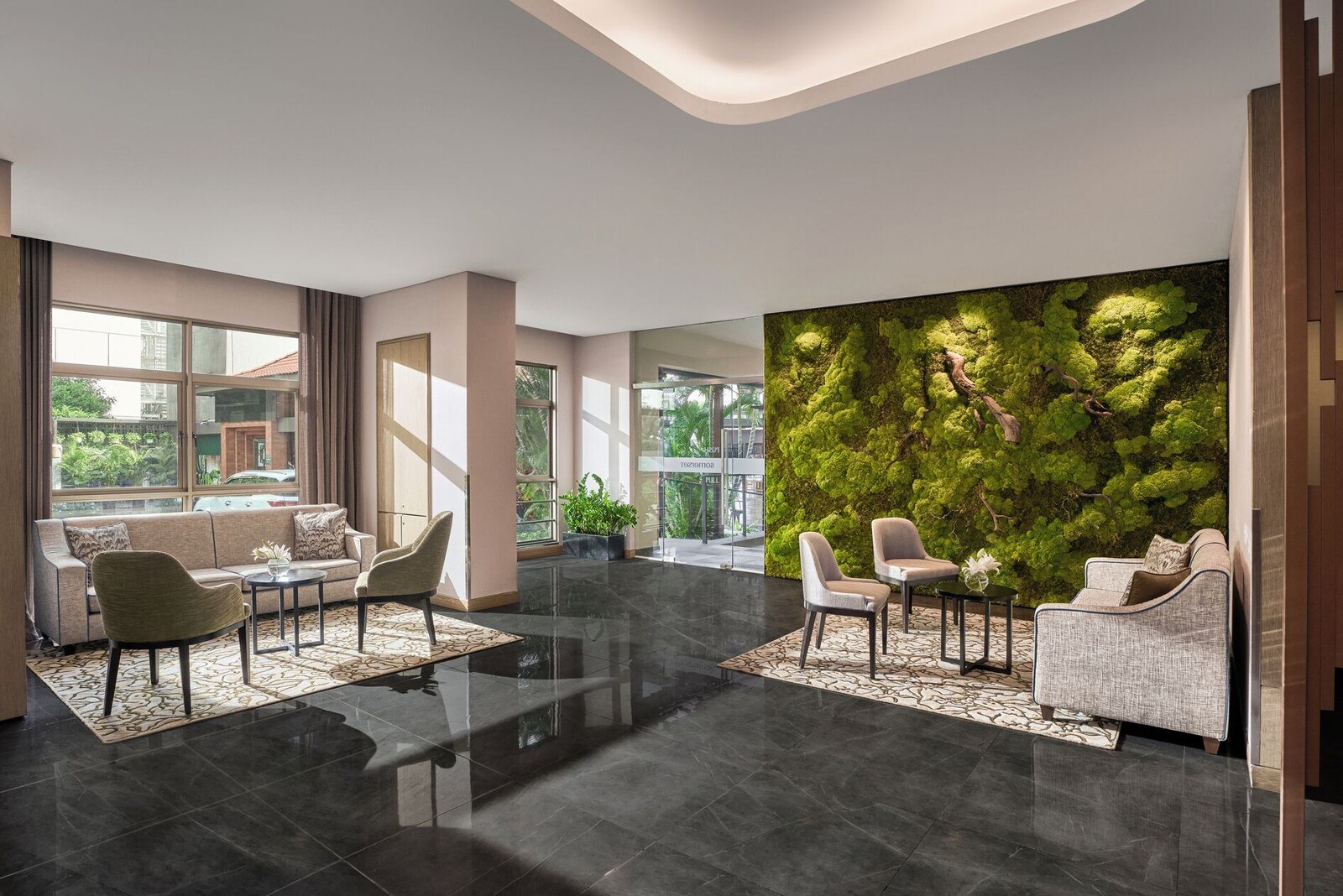 A modern lobby with a green moss wall, seating area, and large windows. - Somerset Ho Chi Minh City (Ho Chi Minh City)