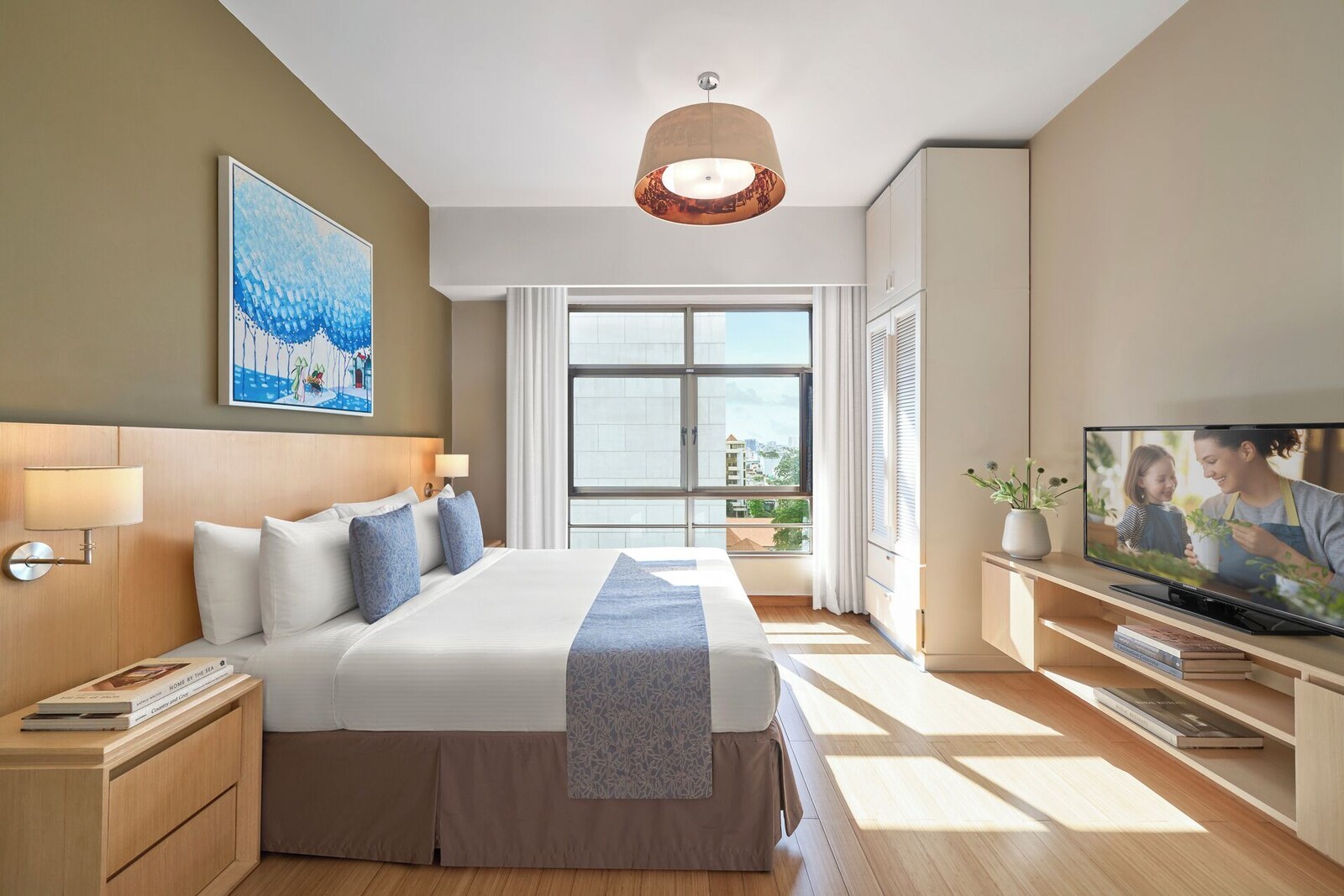 A modern hotel room with a large bed, a television, and a window with a city view. - Somerset Ho Chi Minh City (Ho Chi Minh City)